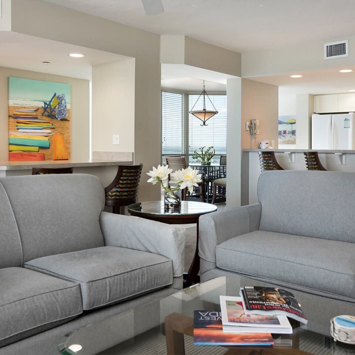 Living room with gray sofas, coffee table and artwork overlooking kitchen