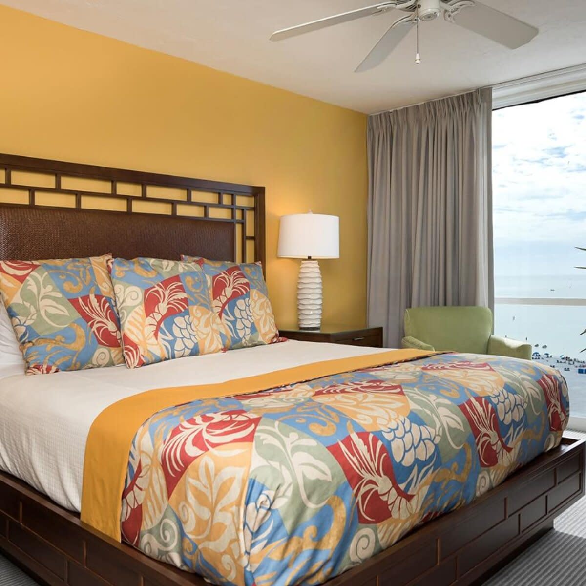Bedroom with king bed, colorful floral bedding and ocean view from window