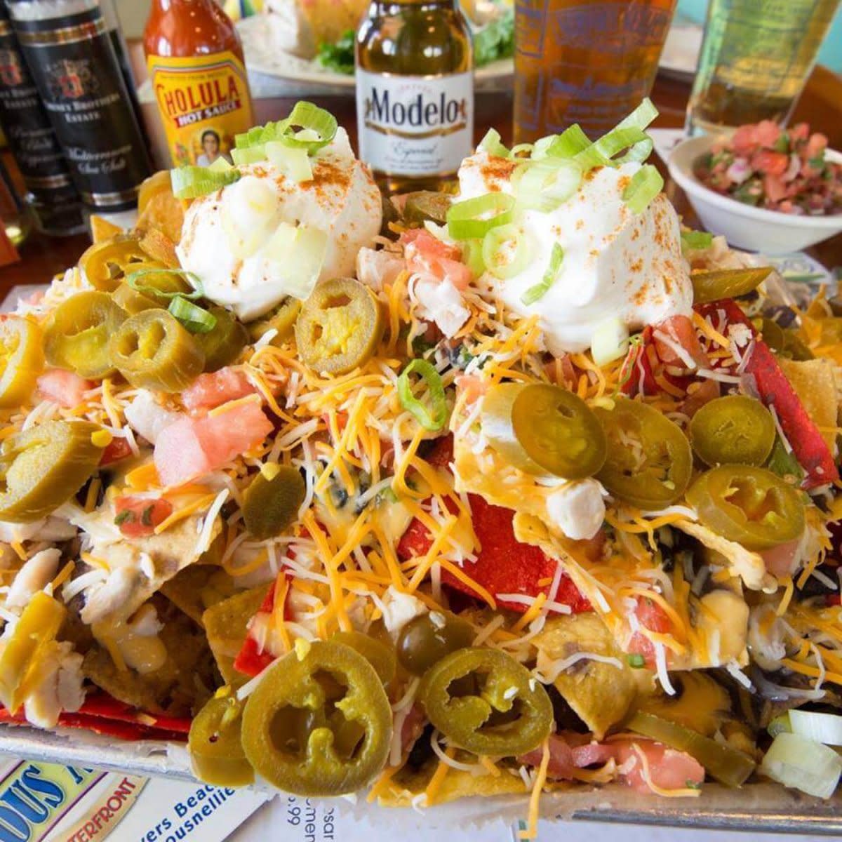 Loaded nachos piled high with jalapeños, cheese, sour cream, diced tomatoes, and green onions.