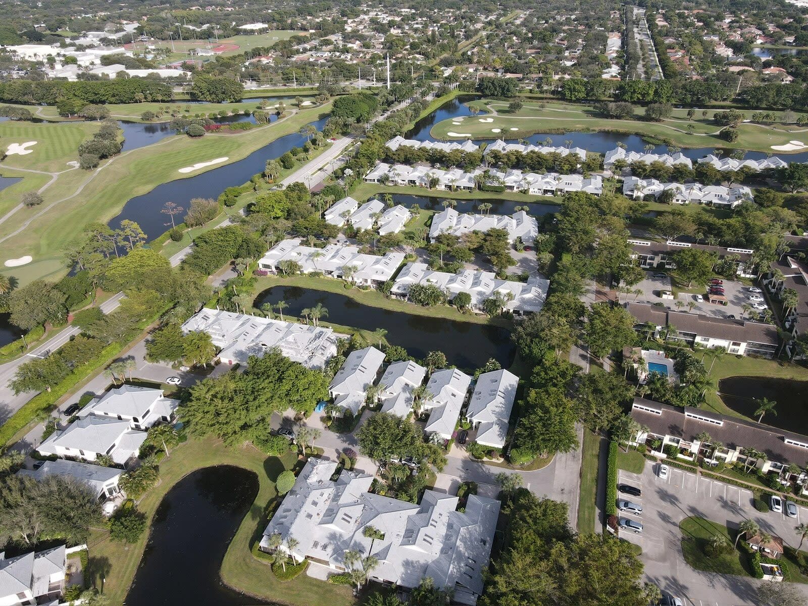 Aerial view of white tile roofs across the Waters Edge golf community in Boca Raton