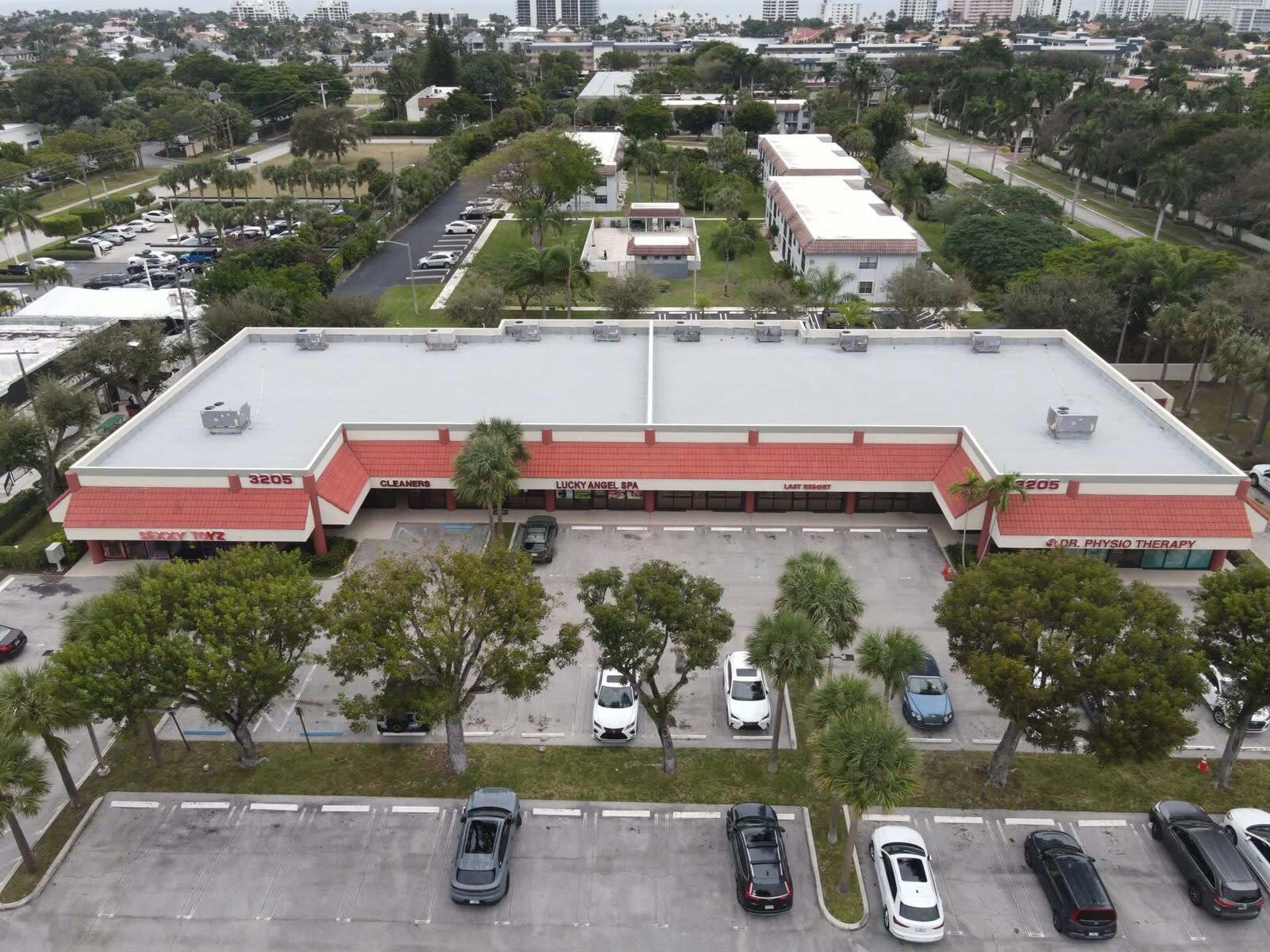 Aerial view of a white flat roof on a shopping plaza with red awnings in Delray Beach