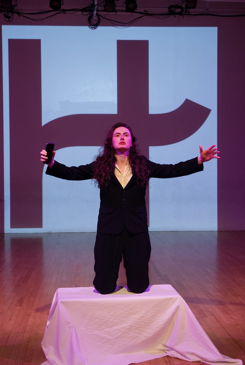 Photo of a woman with brown curly hair kneeling in front of a giant H (the Hinge logo).