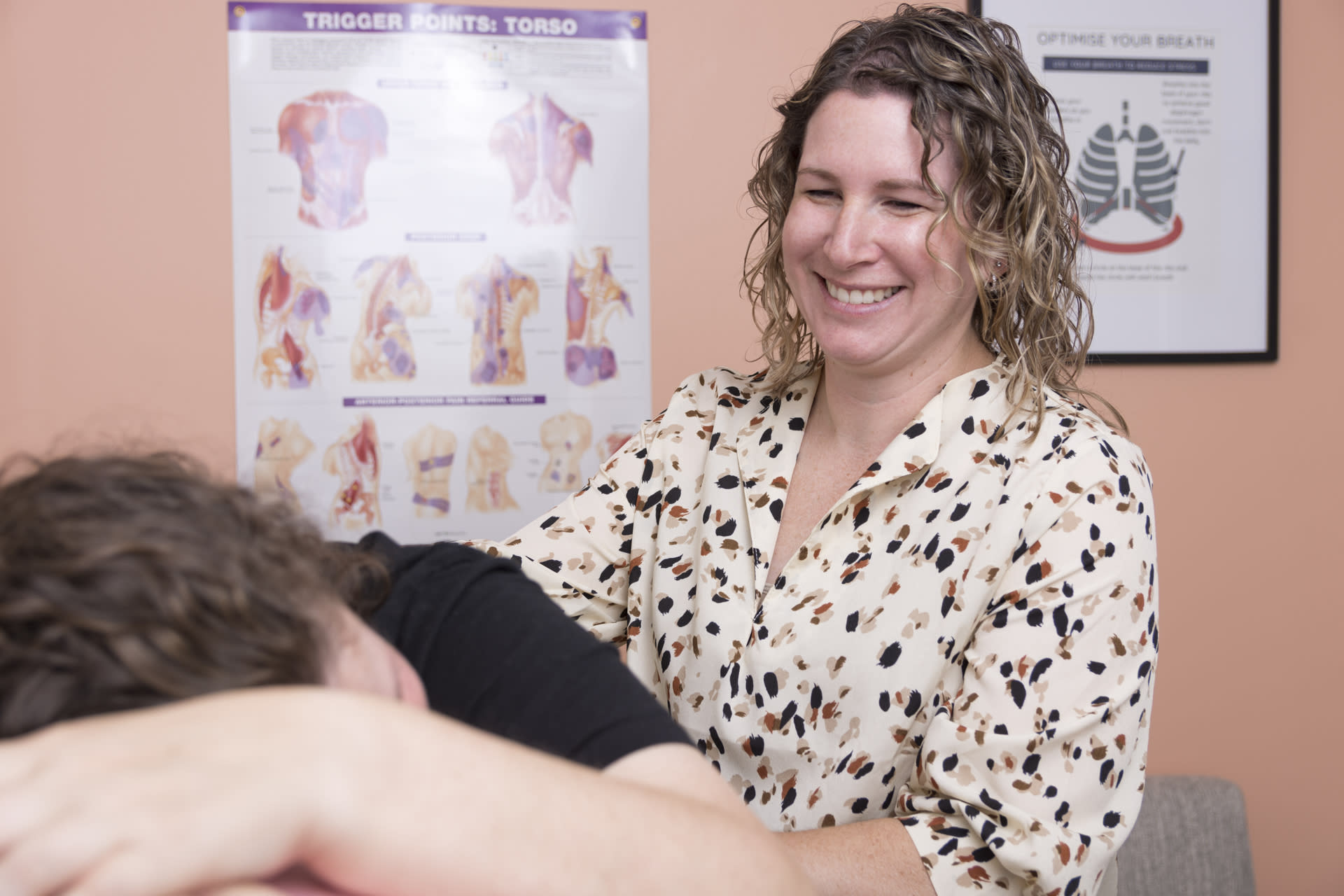 physical therapist smiling at patient lying over exercise ball