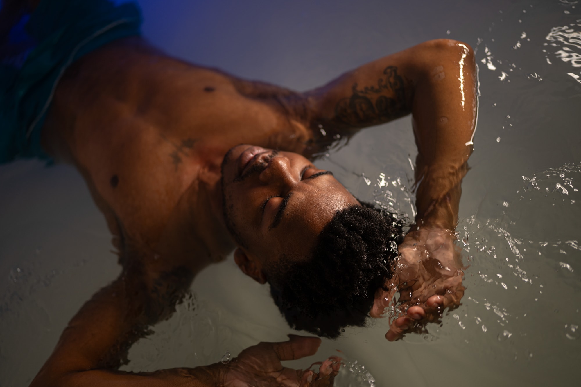 Man floating in a sensory deprivation tank, relaxing with arms behind head