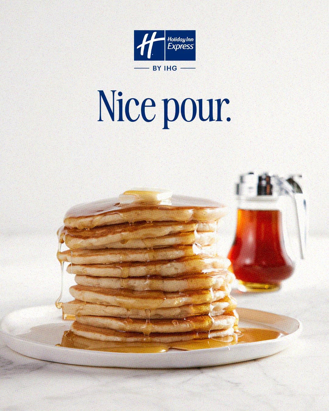 Holiday Inn Express ad features tall pancake stack drizzled with syrup, bottle beside plate, tagline Nice pour.