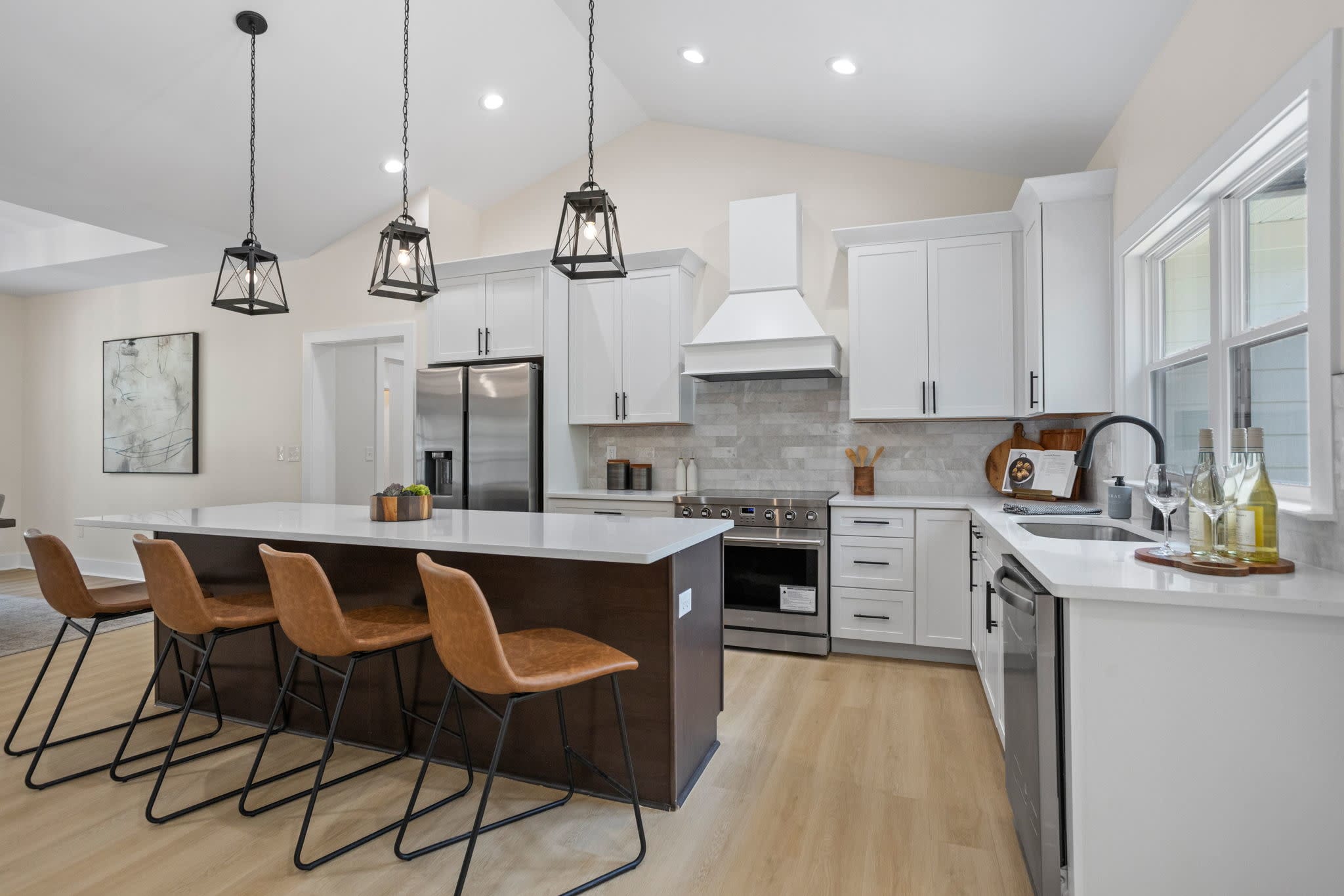 Modern kitchen featuring white cabinetry, a contrasting dark wood island, quartz countertops, black pendant lights, and stain