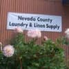 Nevada County Laundry & Linen Supply sign on building with big pink flowers in front