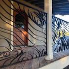 Merlin Metals- metalwork creating a partition of metal ribbons and swirls in front of a builiding