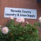 Nevada County Laundry & Linen Supply sign on building with big pink flowers in front