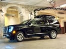 Blue Sky Limo GMC Yukon Denali with a rooftop cargo box at a Vail hotel entrance