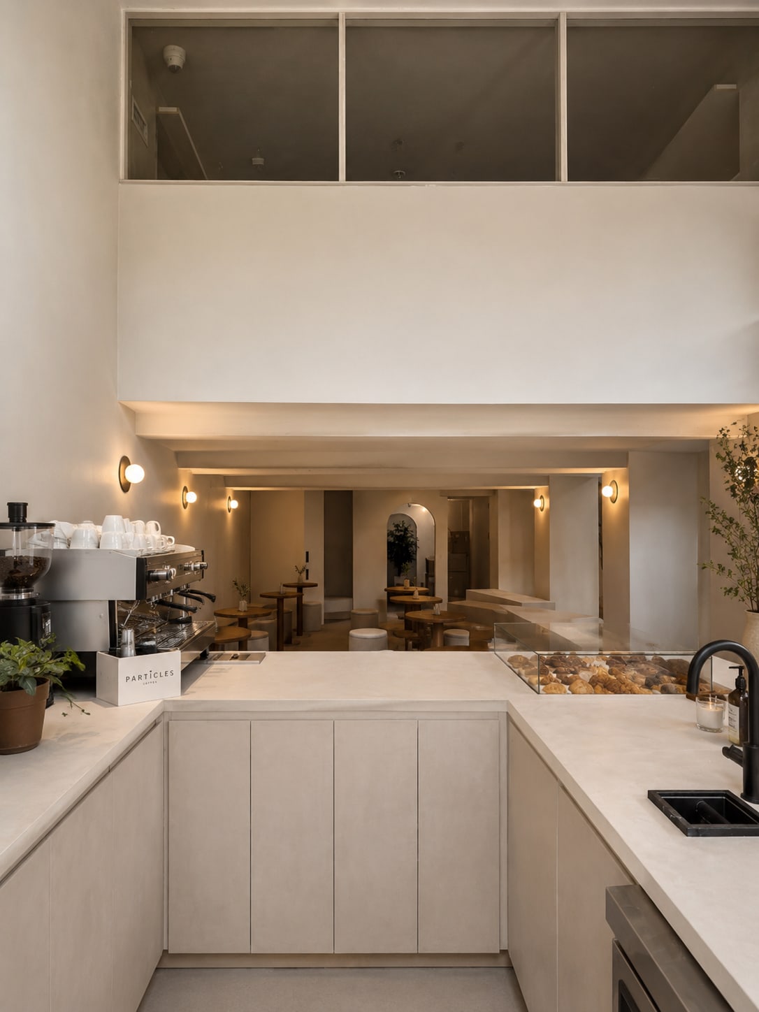 Particles café counter at 3696 West 8th Ave featuring custom stone-look millwork, espresso equipment, pastry display, warm wa