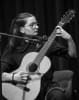 Woman playing a guitar while sitting