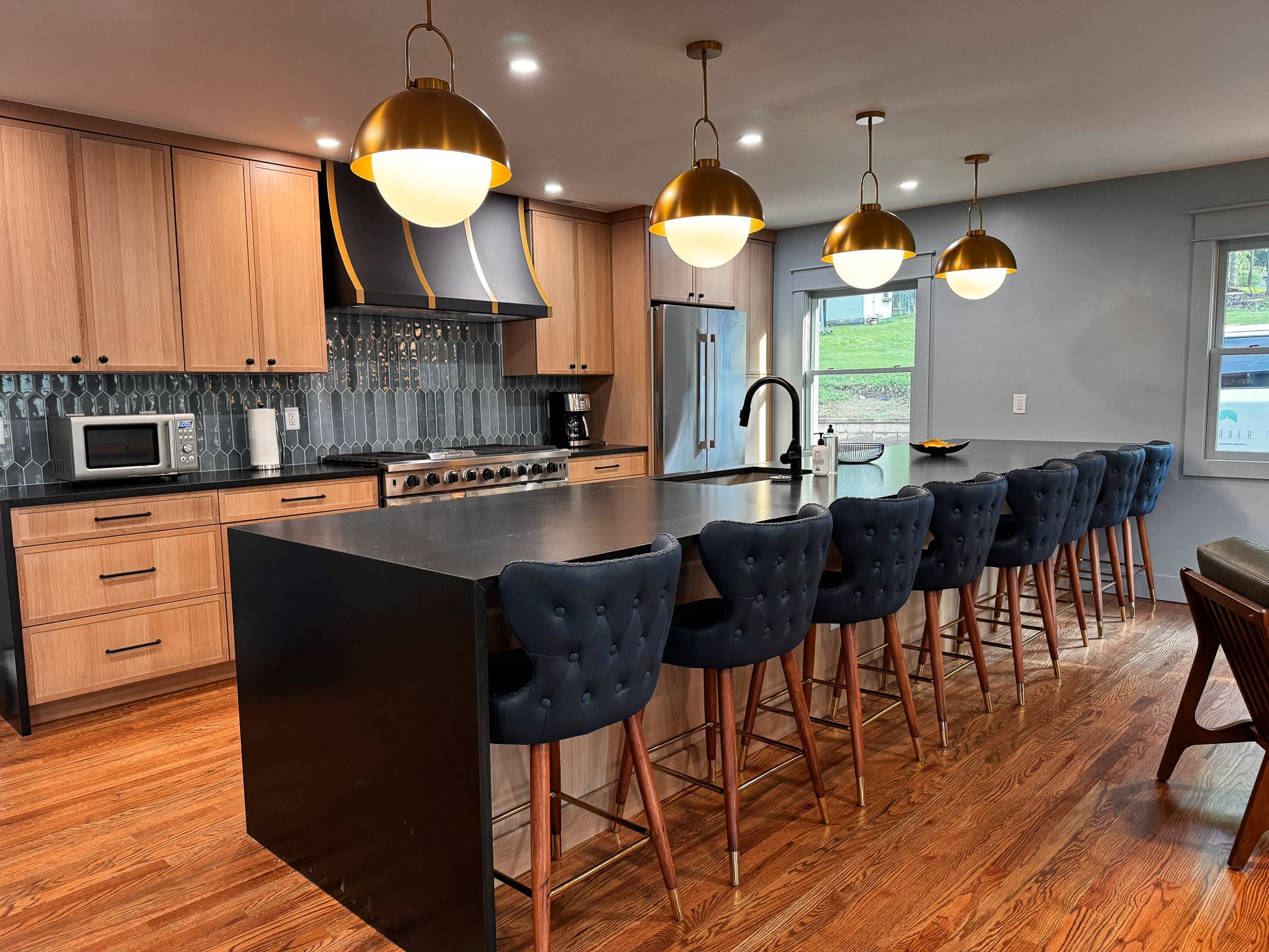 Modern gourmet kitchen with a large island, seating for ten, custom cabinetry, designer pendant lighting, and upscale finishe