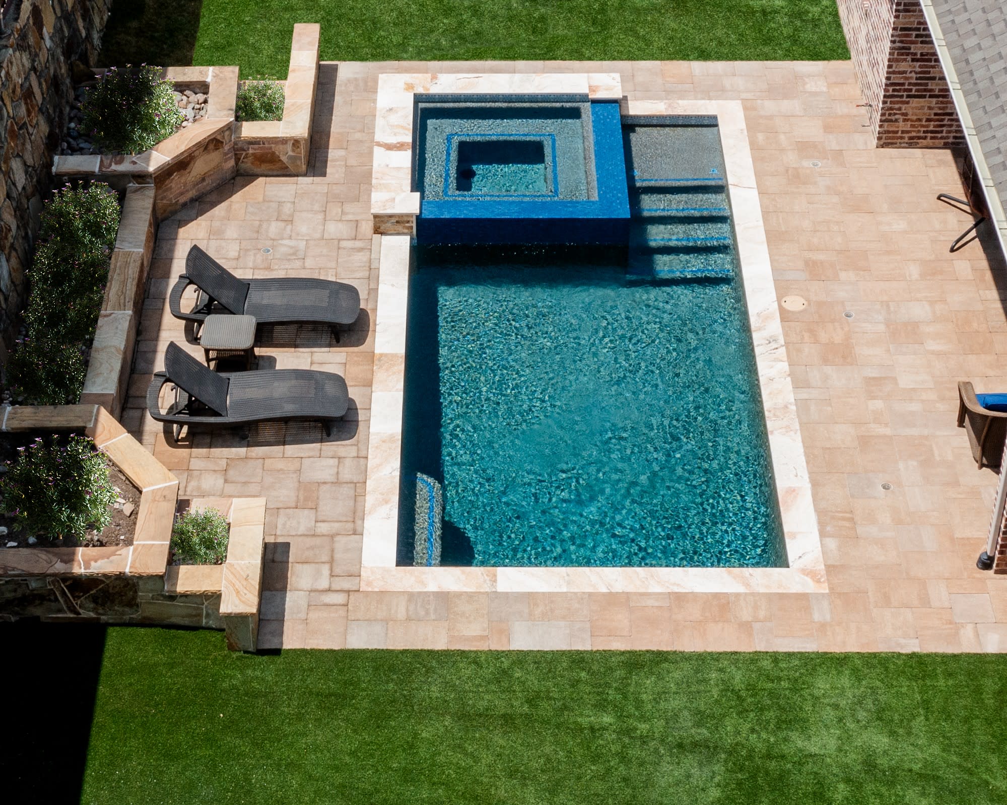 Luxury custom gunite swimming pool and raised spa with travertine decking built by Canyon Oak Pools in Prosper, Texas.