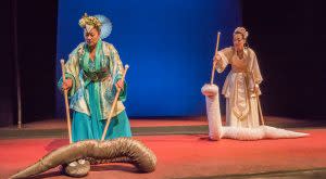 CATS stage- two women dressed in beautiful, traditional Asian attire on stage moving silken snake puppets