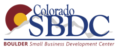 A Boulder SBDC advisor, Carolina Manross, is instructing a workshop with a blue wall background.