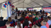 A large crowd of people seated inside a tent listening to remarks during MCC's Workforce Development Corridor Groundbreaking