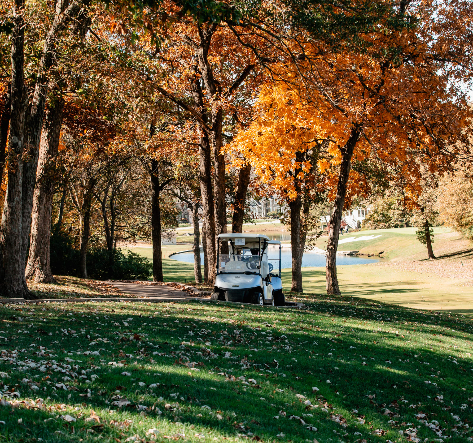 A golf cart drives across a scenic golf course at Lakewood Oaks for Holes FORE Homes event.