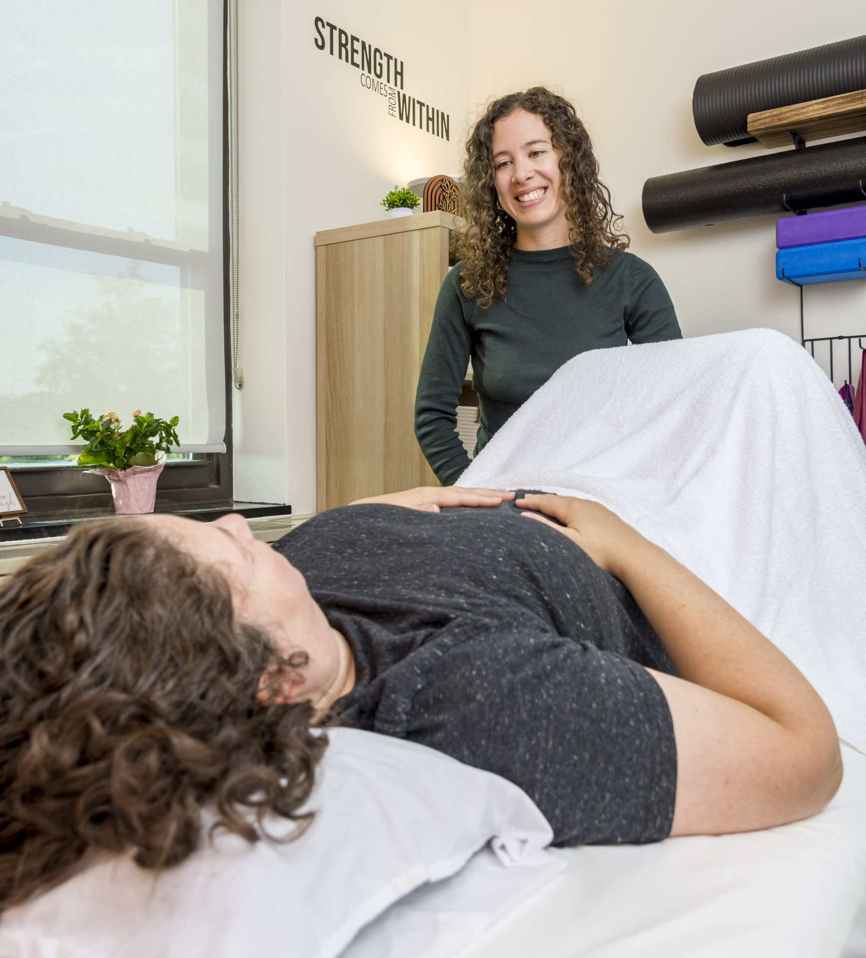 physical therapist smiling at patient who is lying on her back on the table