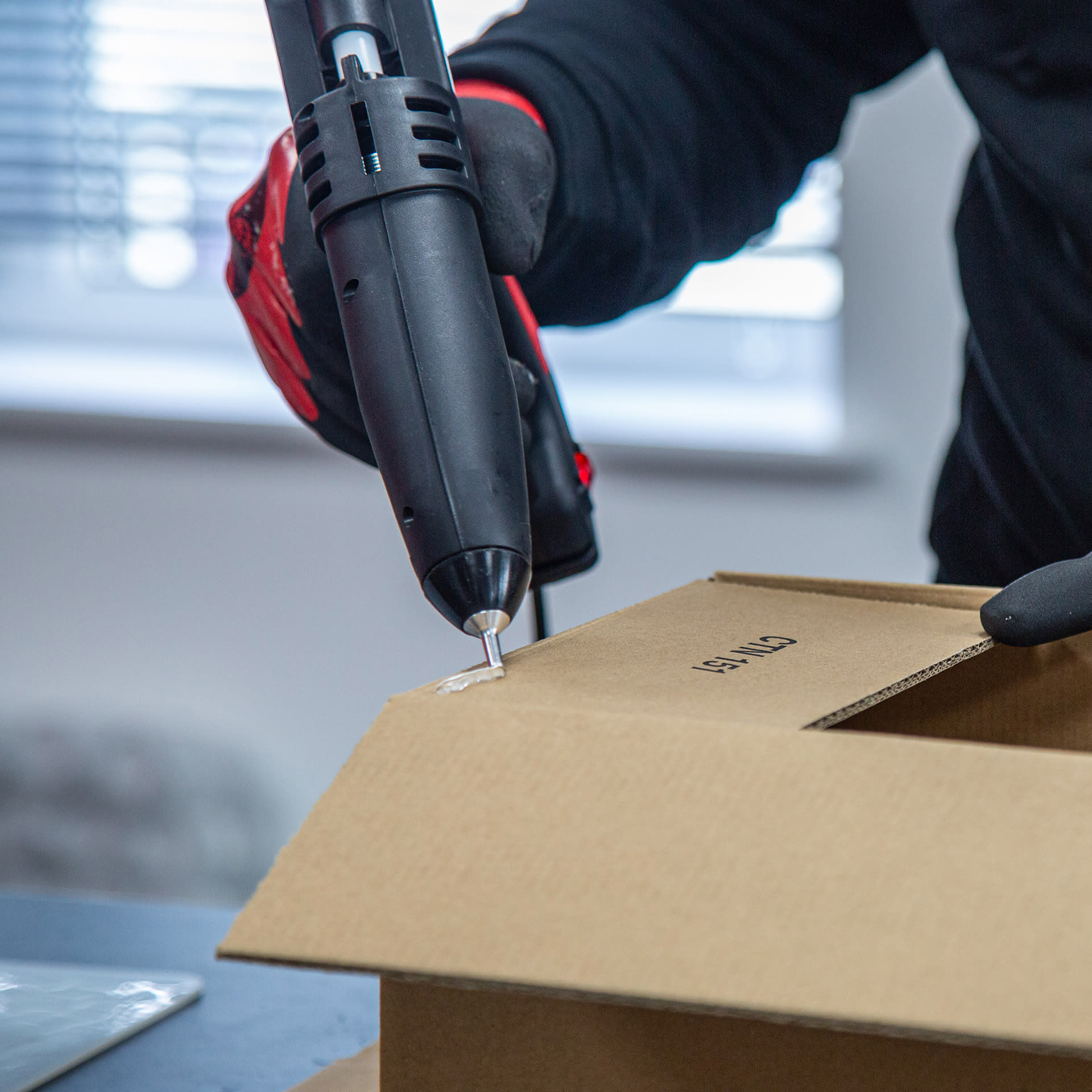 Tec hot melt applicator applying Tecbond 114 to a cardboard carton to seal it