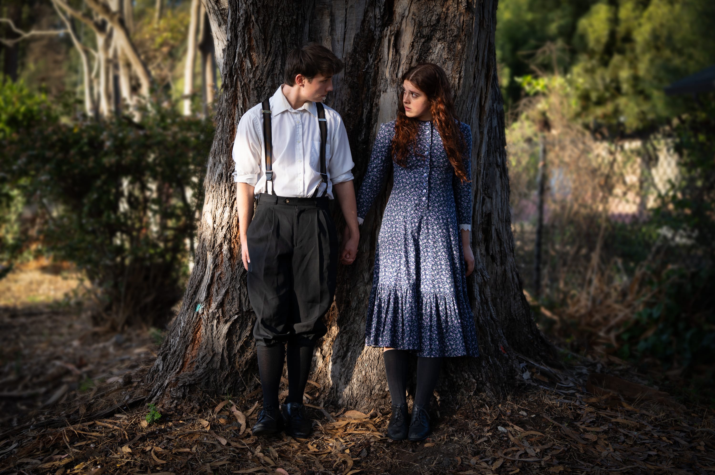 to actors holding hands in front of a tree