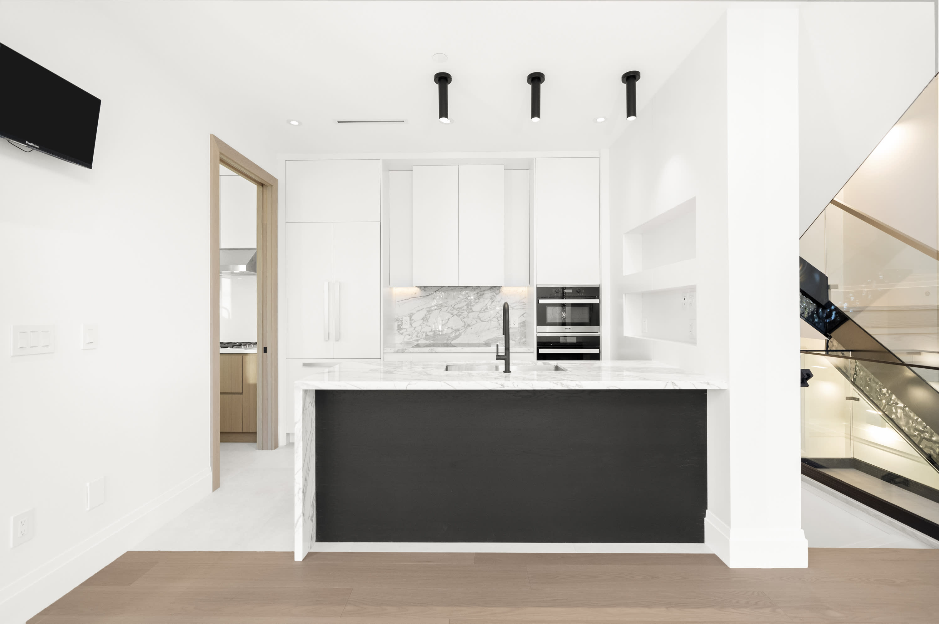 Modern custom home kitchen at 3802 West 22nd Avenue featuring white cabinetry, marble surfaces, black accents, built-in appli