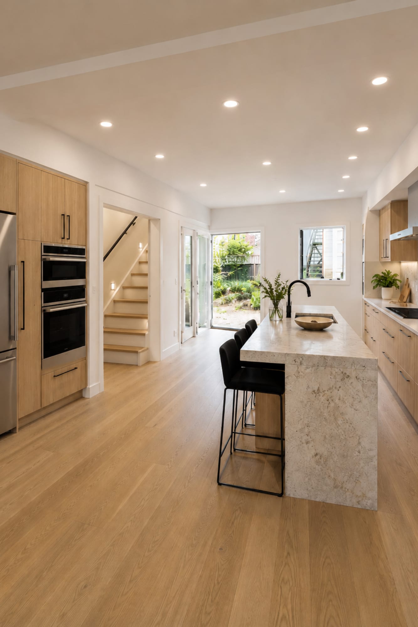 Modern laneway home kitchen at 5741 Beckley featuring light wood cabinetry, stone waterfall island, black fixtures, built-in