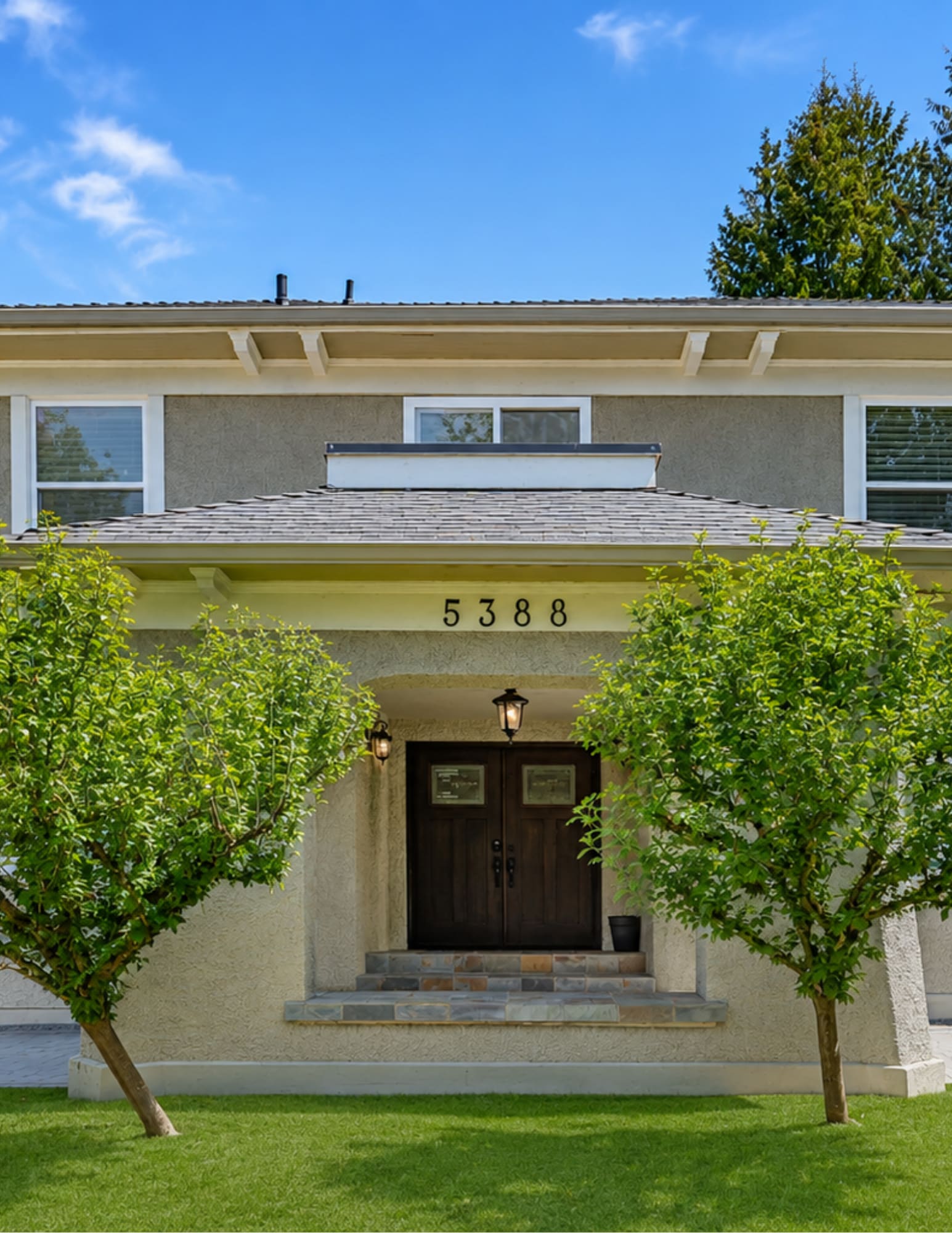 Renovated home exterior at 5388 Cypress featuring a refreshed entry, double wood doors, tiled front steps, mature landscaping