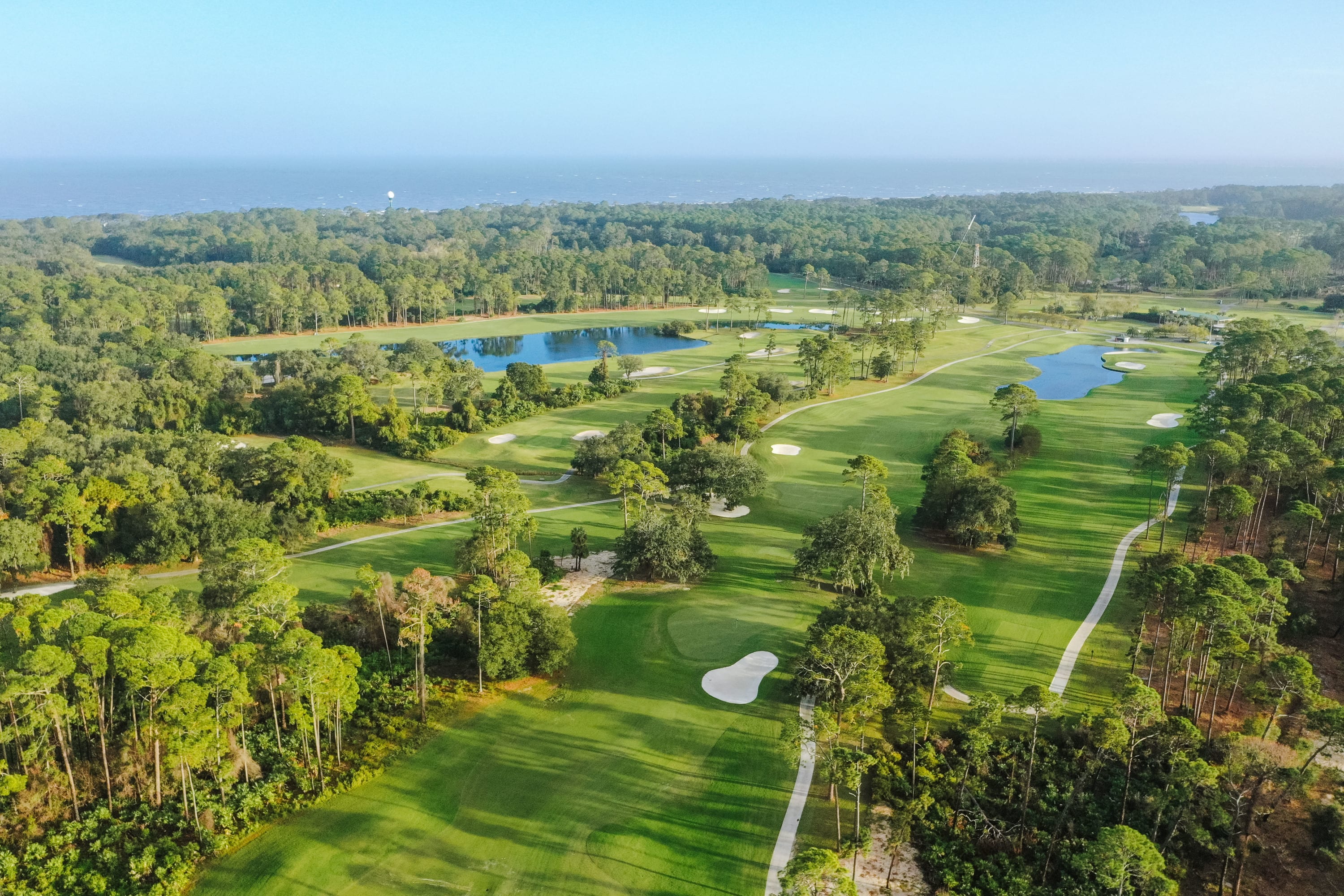 Aerial shot of the Jekyll Island golf courses featuring pristine greens and fairways, coastal woodlands, and lakes.