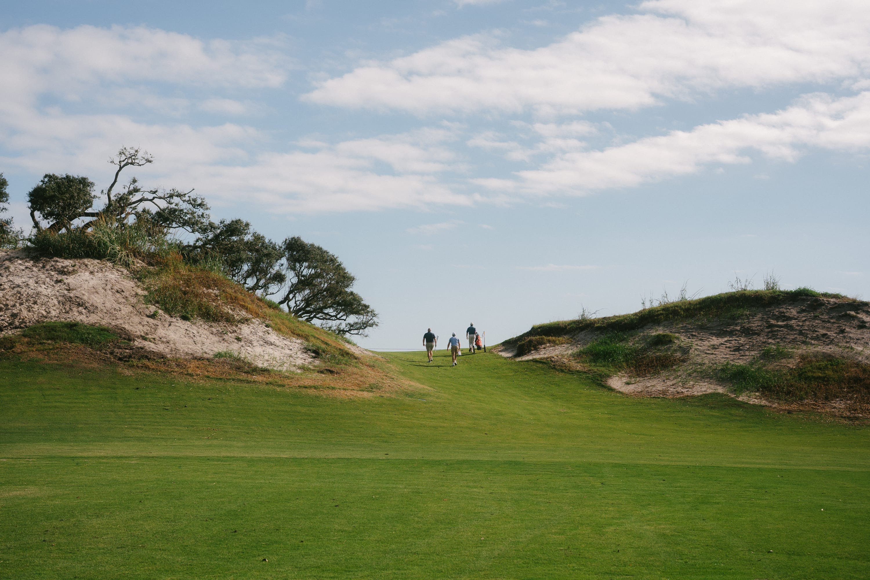 Mae West hole at Great Dunes Golf Course on Jekyll Island featuring a green fairway nestled between two sand dunes.