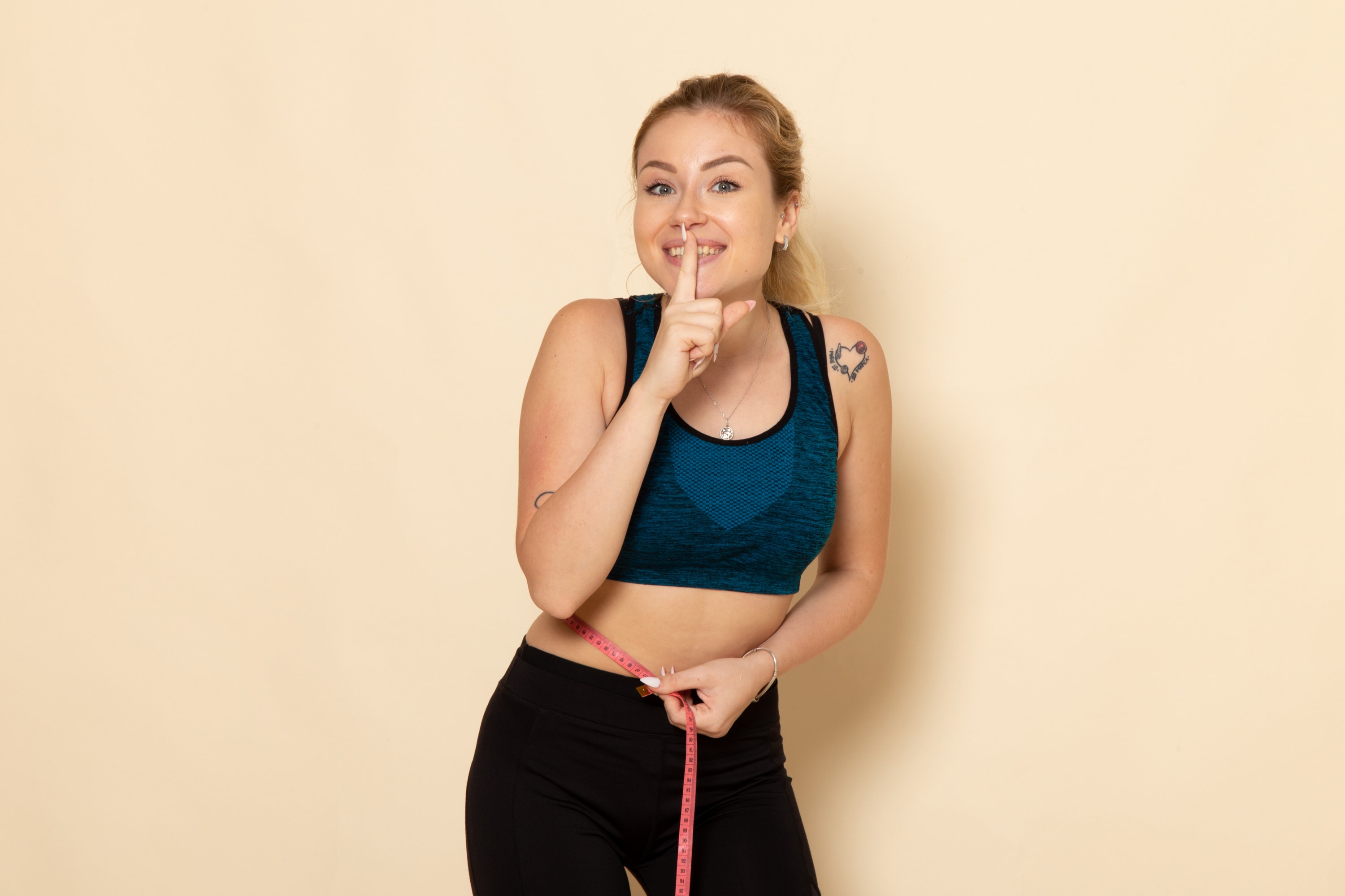 Woman measuring her waist with a tape measure to represent medical weight loss and wellness goals