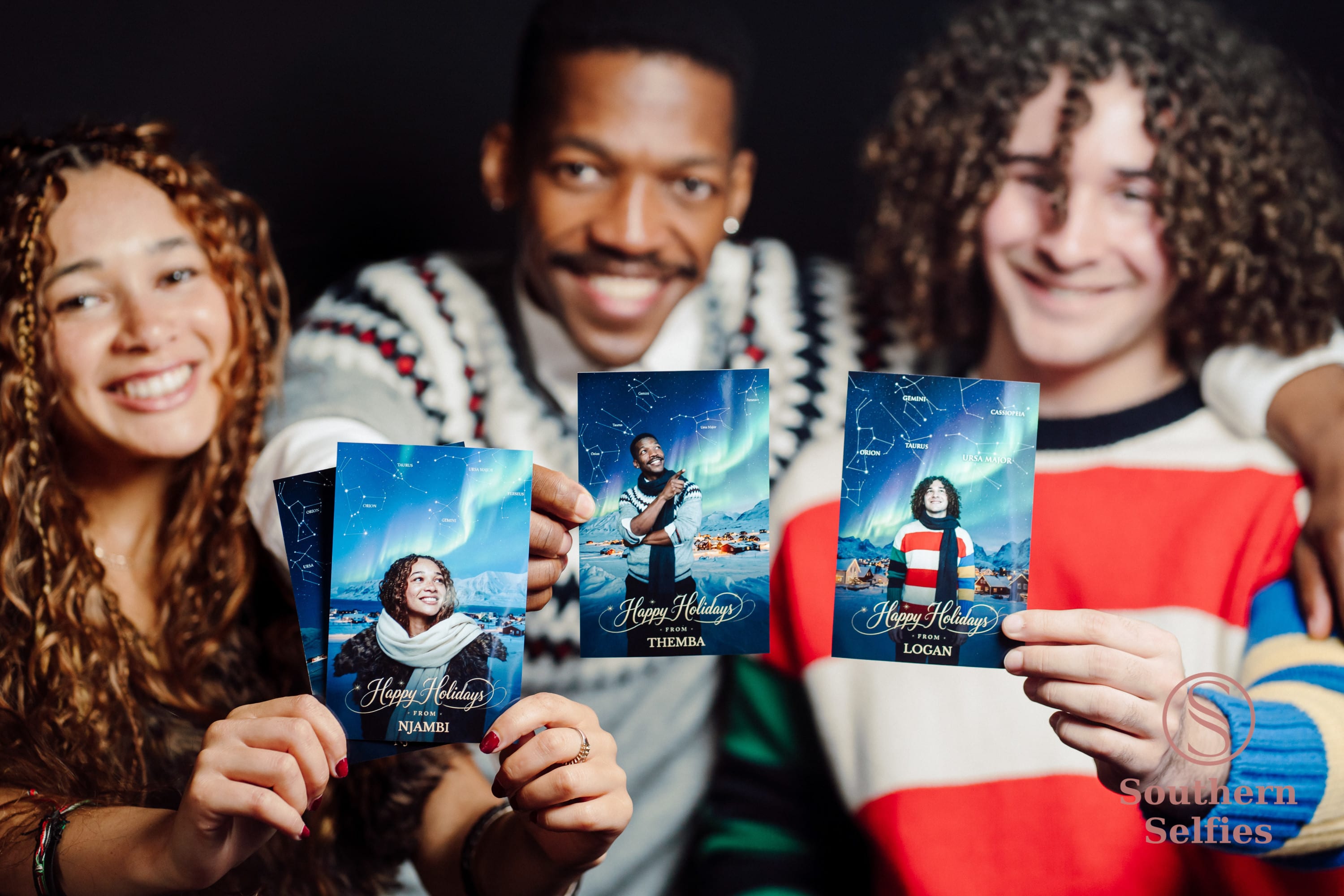 Group of guests holding up their printed holiday photos at a Christmas party.