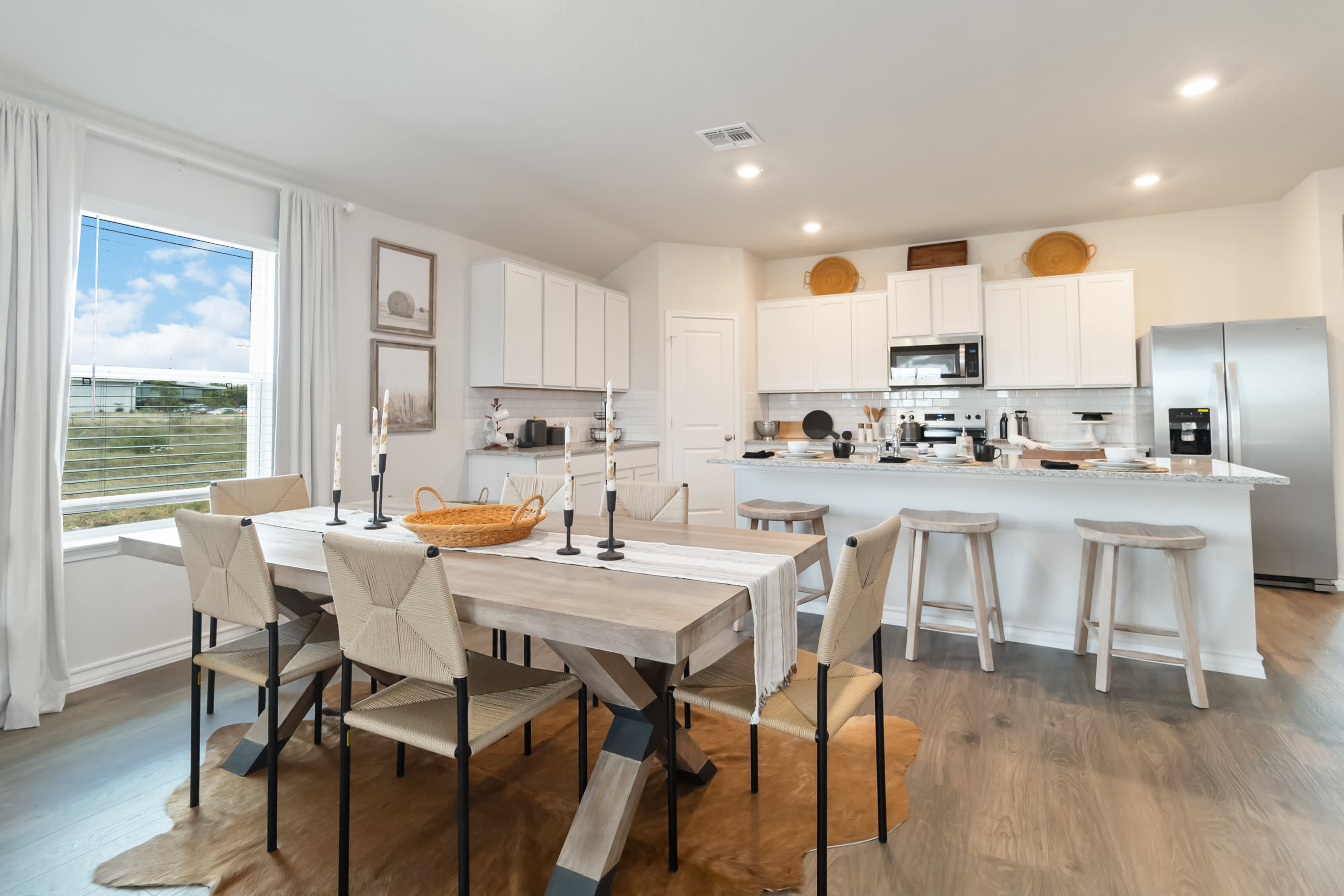 open concept dining area flowing into kitchen with large kitchen island, quartz counters and stainless steel appliances