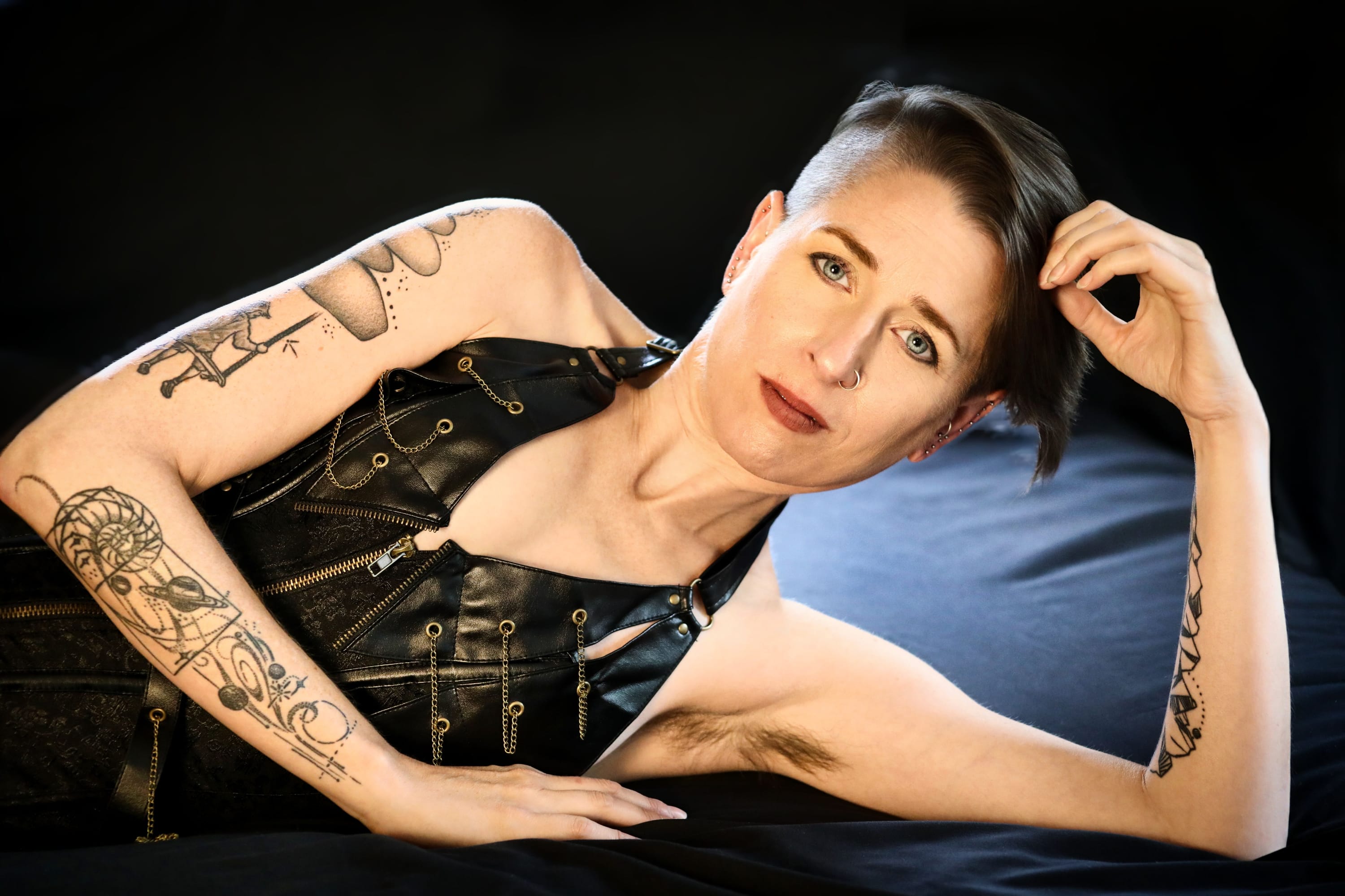 Portrait of person in black halter showcasing arm tattoos.