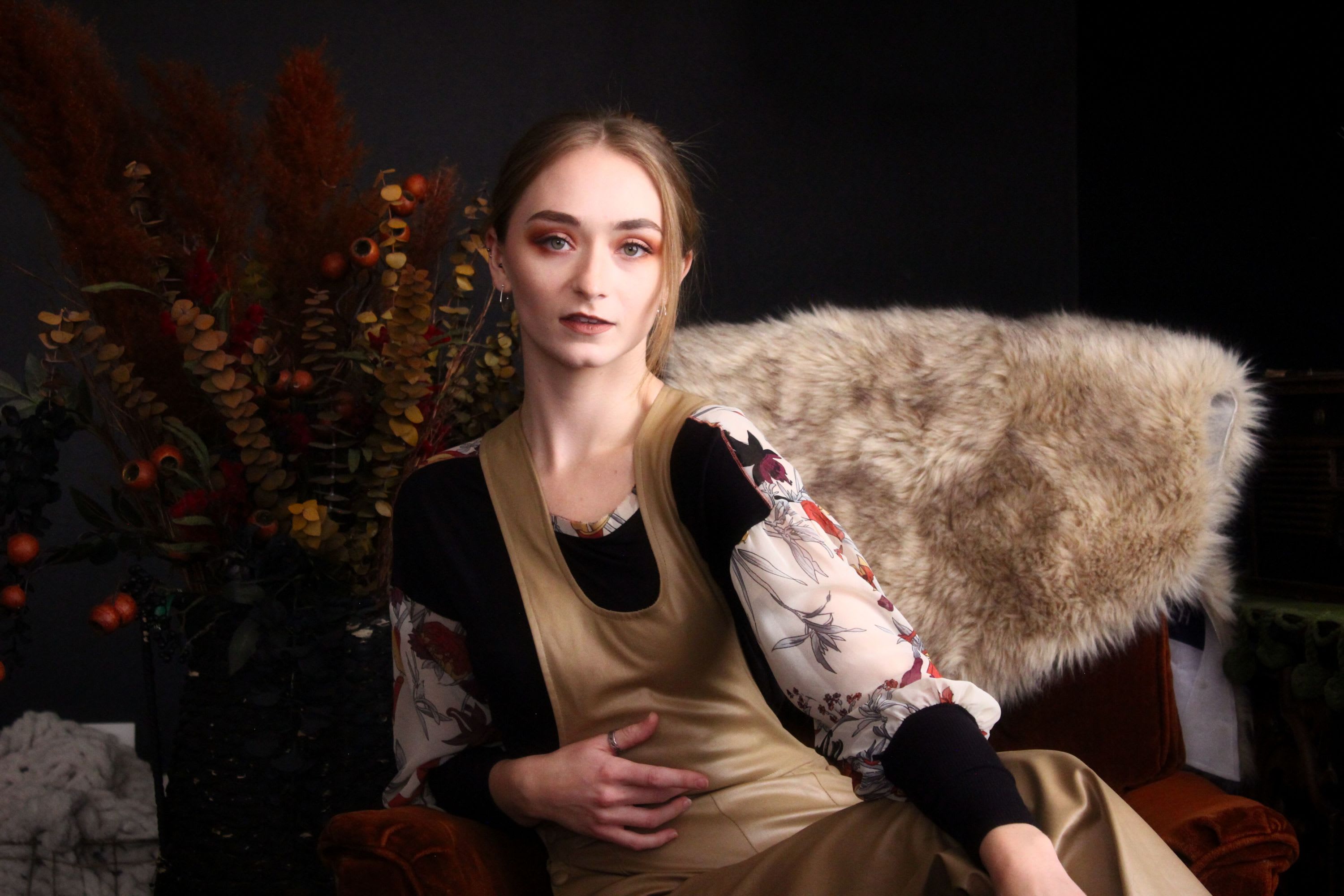 Fine art portrait of woman in cream jumper sitting on a velvet chair