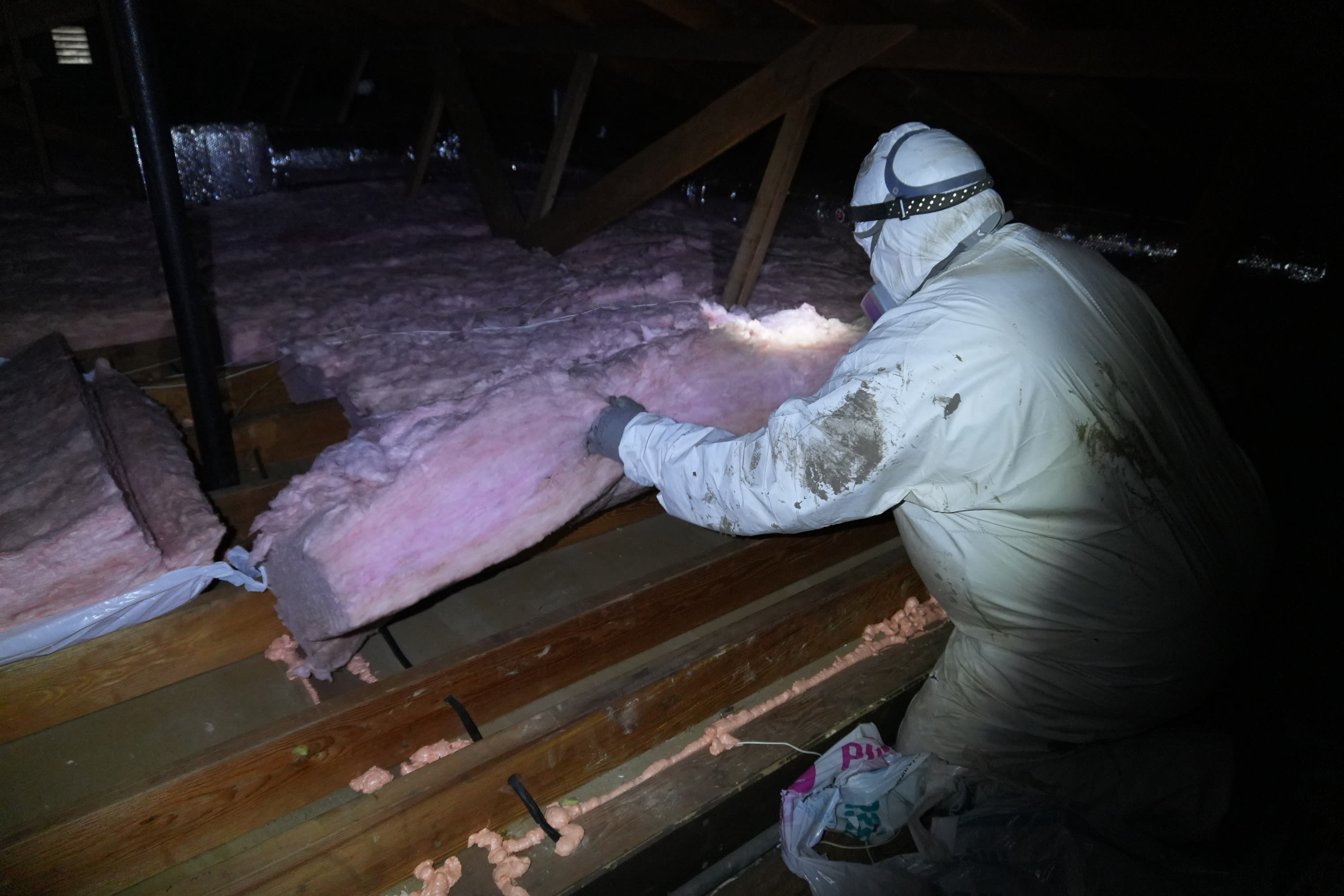 New insulation being installed across attic floor to improve heat retention and overall home performance.