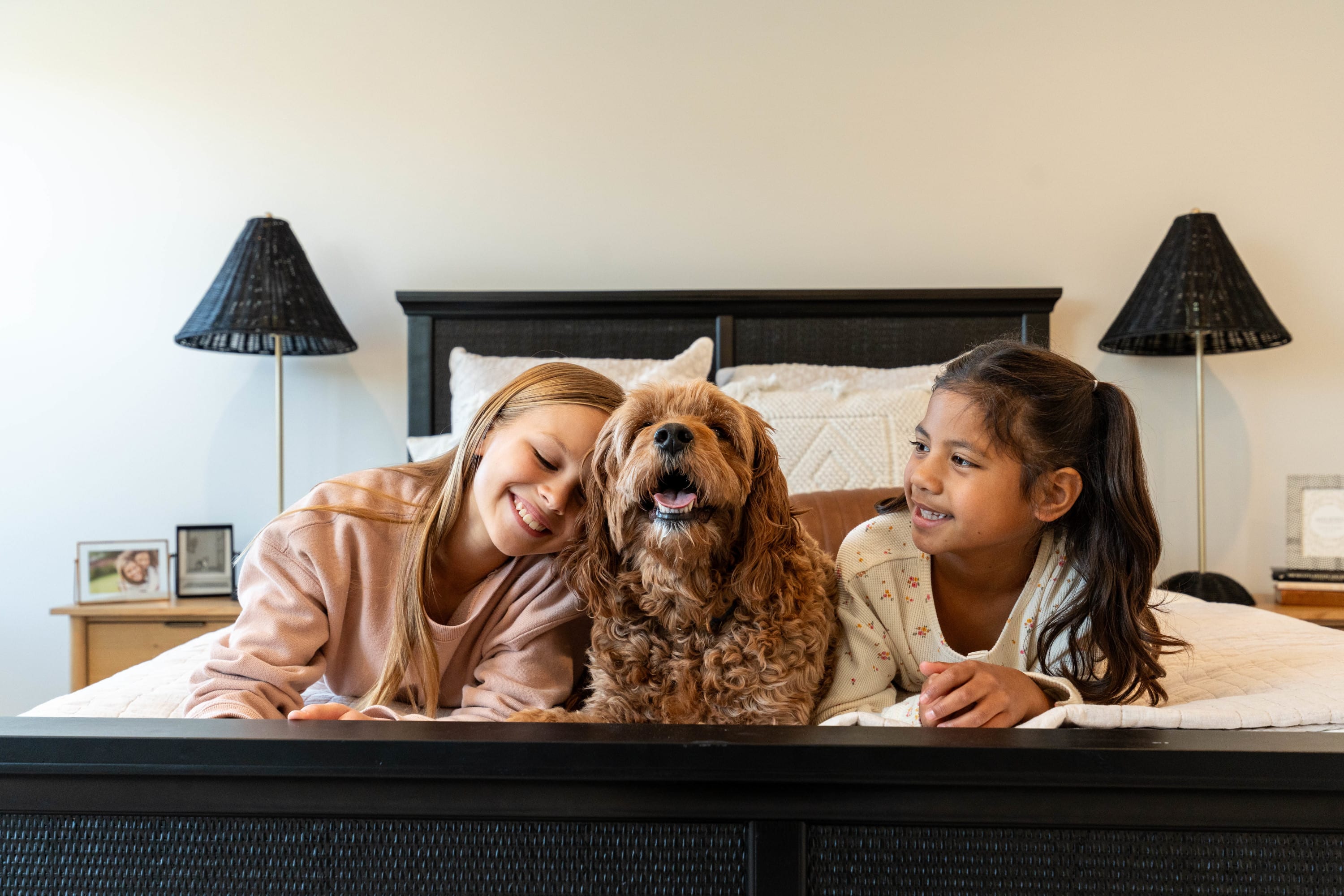 Alt Text Two children and a dog relaxing on a bed in an Interra Homes bedroom.