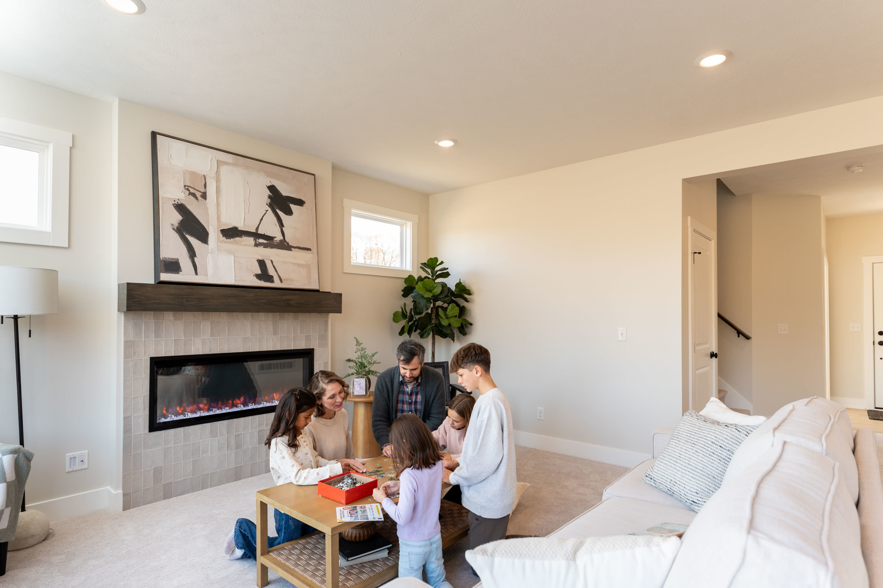 Family playing a board game together in an Interra Homes living room with fireplace