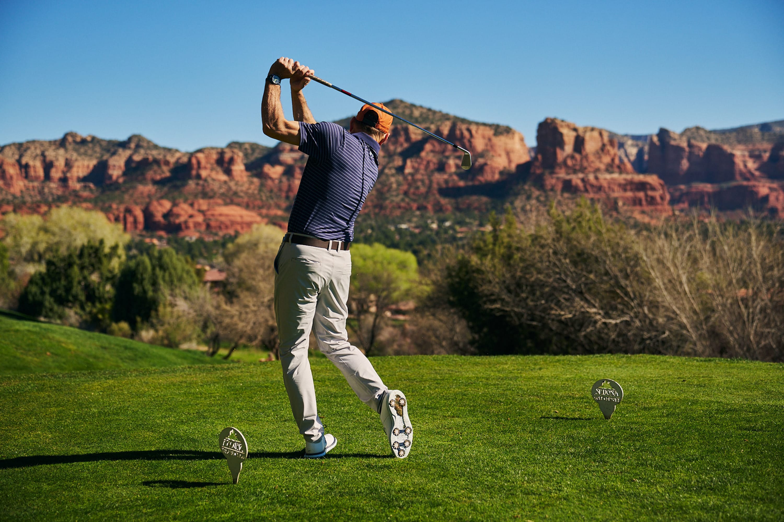 Player teeing off on a championship golf course set against Sedona’s iconic red rock landscape.