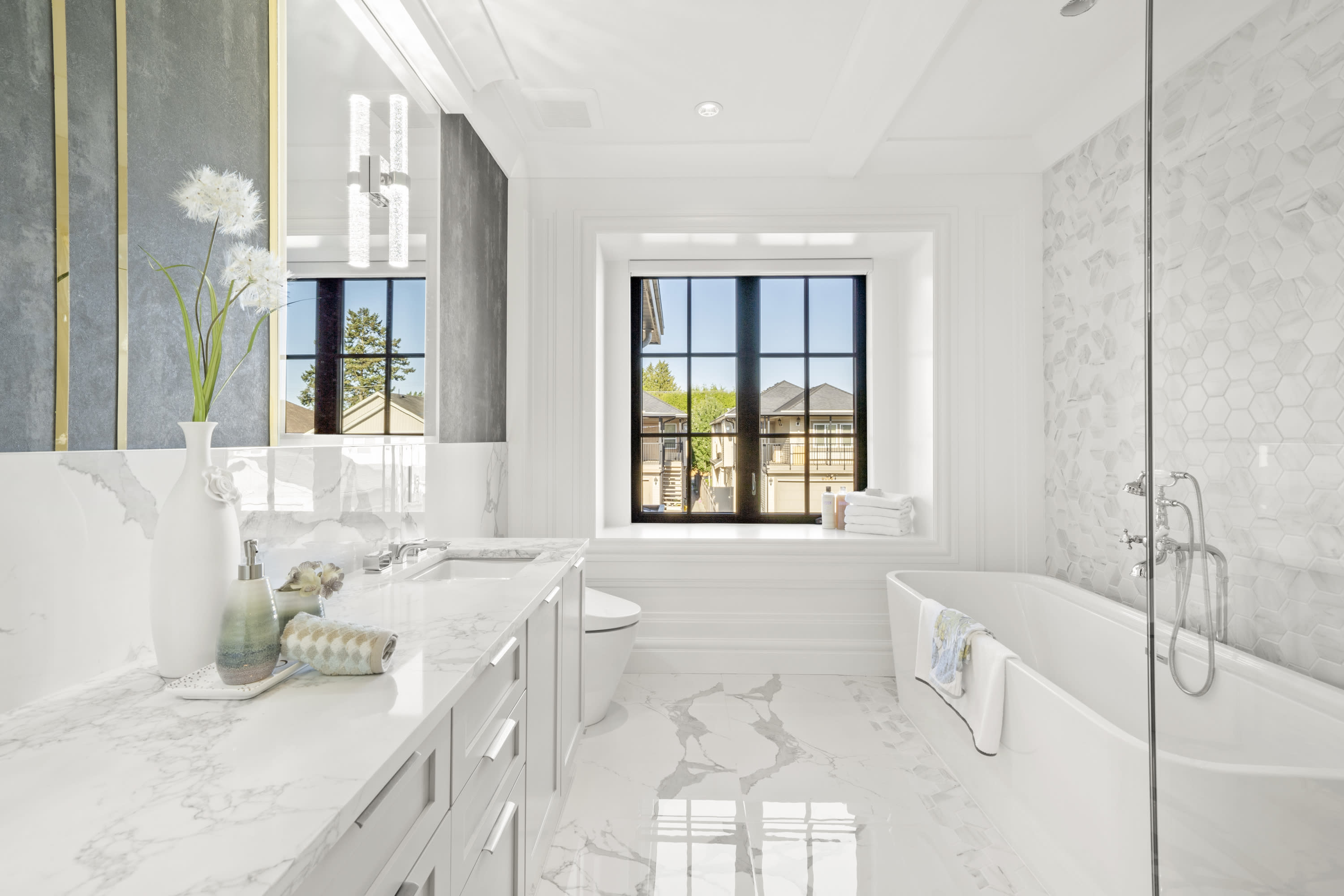 Luxury bathroom at 8080 Alanmore Place featuring marble finishes, a freestanding tub, glass shower, custom vanity, black-fram