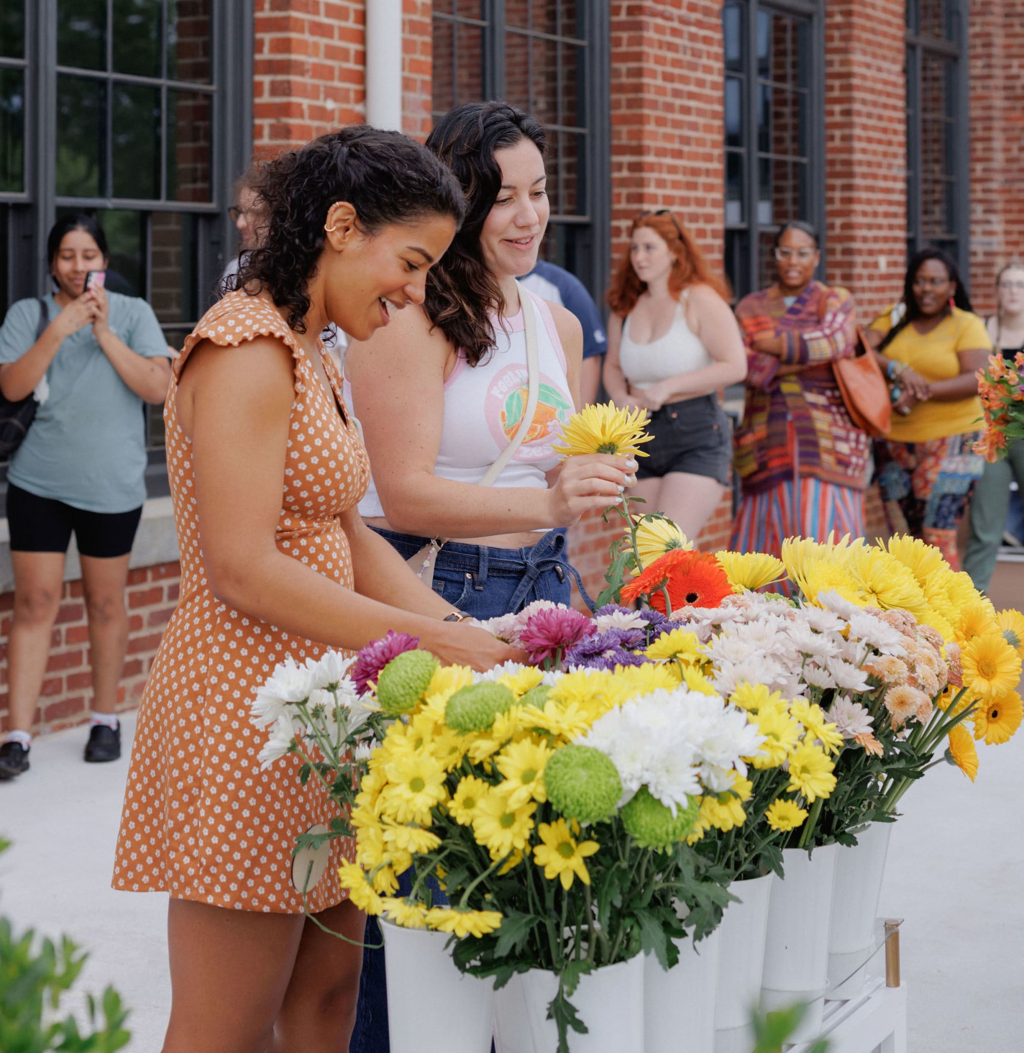 two women building a bouquet from a flower cart