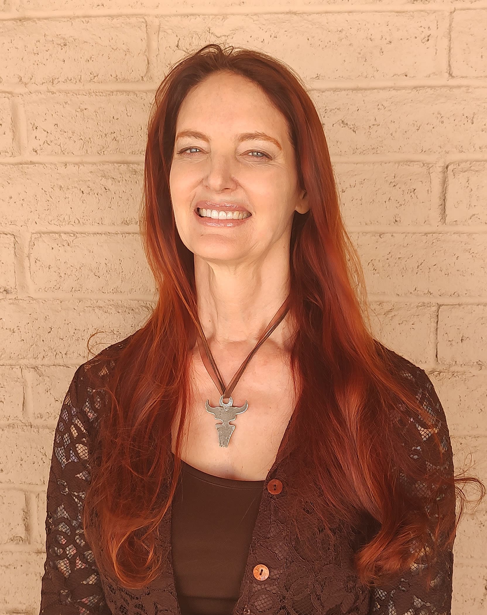 Woman with long read hair wearing a brown top