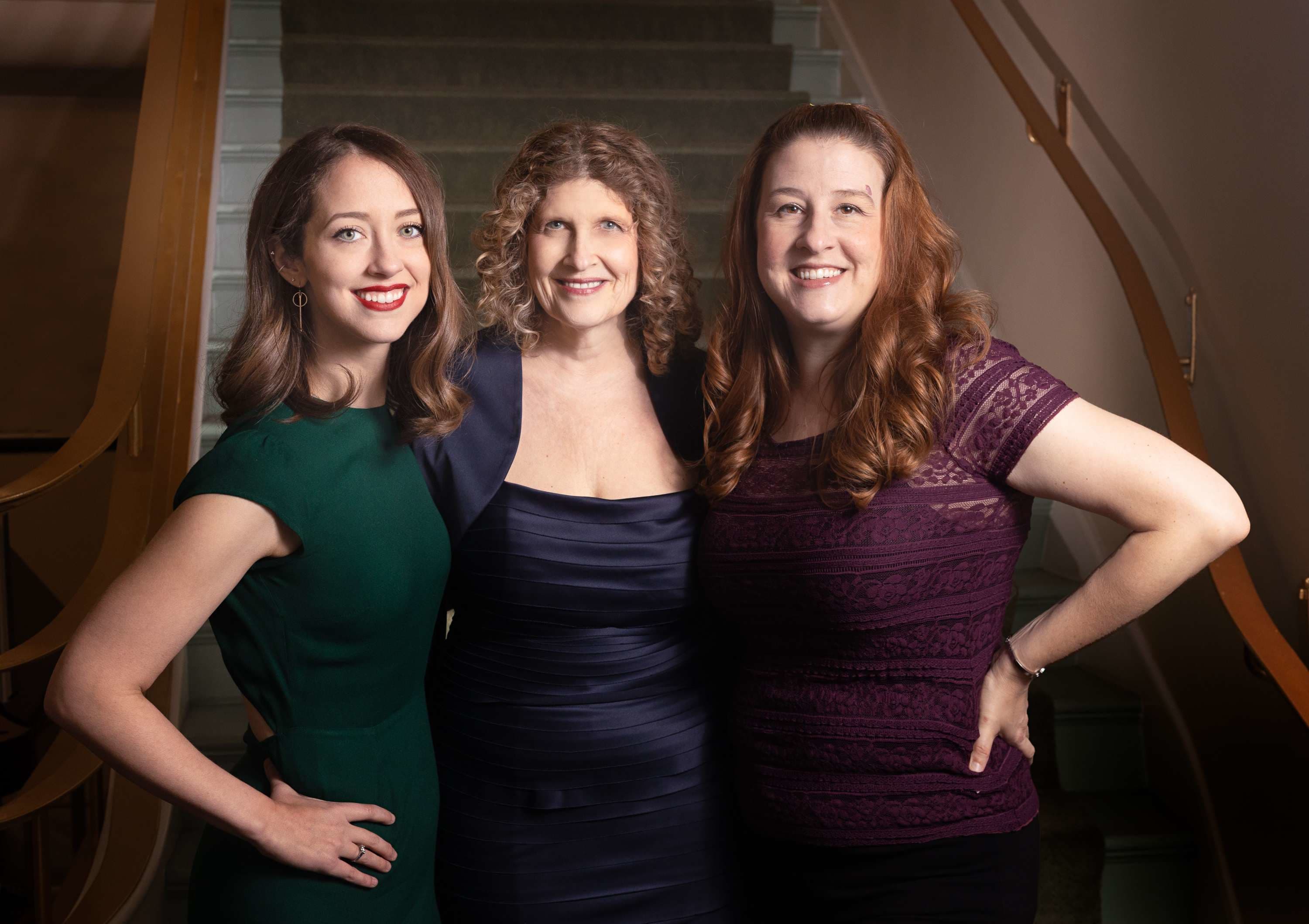 Three women facing the camera in green, purple, and blue clothing
