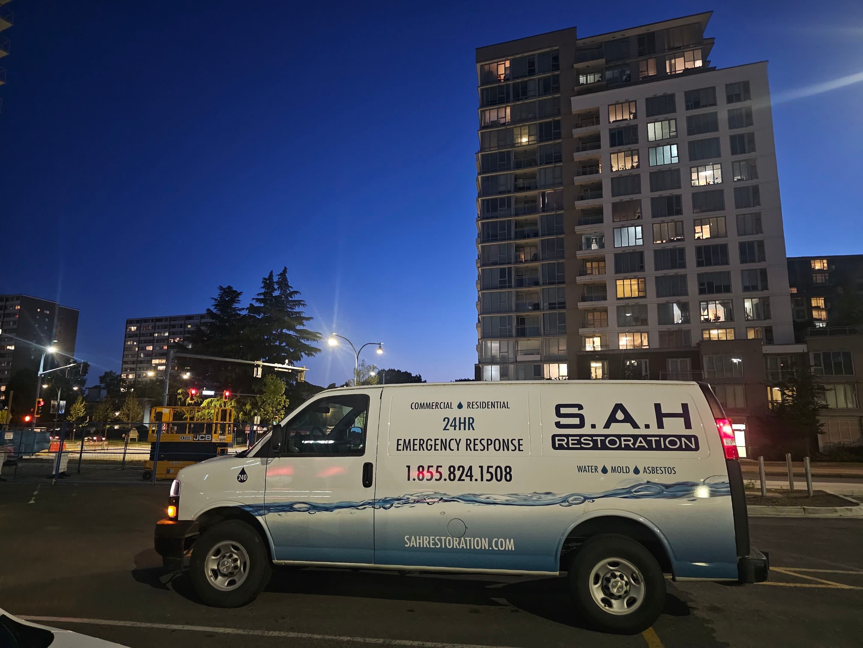 A fleet vehicle is parked outside a city building at dusk.