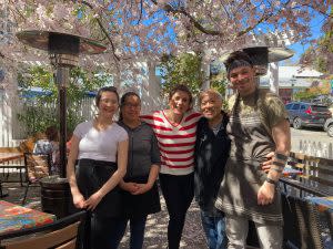 Owner and employees grouped together of Lika's Cafe with beautiful flowering Cherry Blossoms