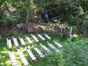 rows of white seating for a wedding, surrounded by greenery and a small waterfall