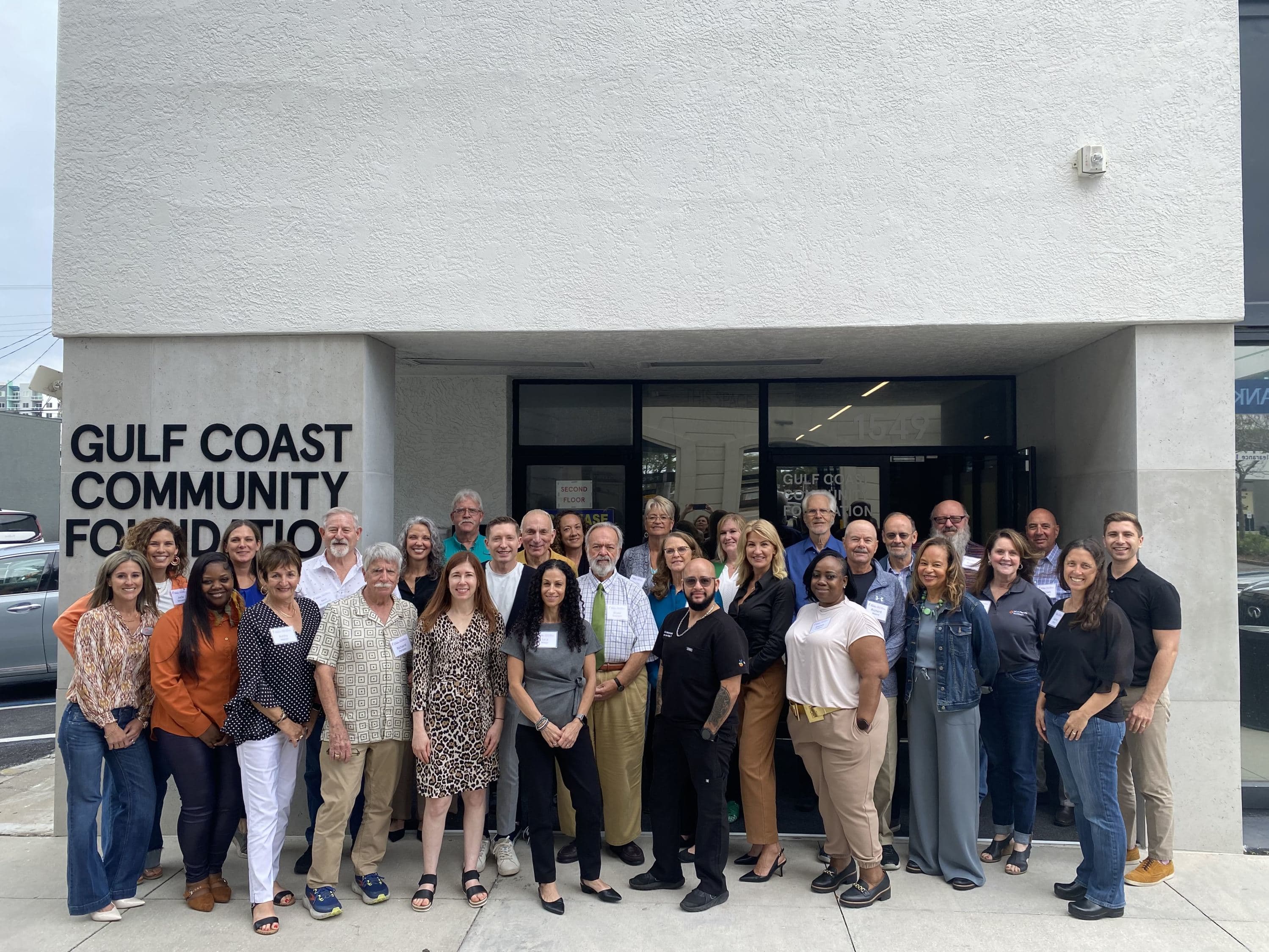 A group of people standing outside of a building and smiling