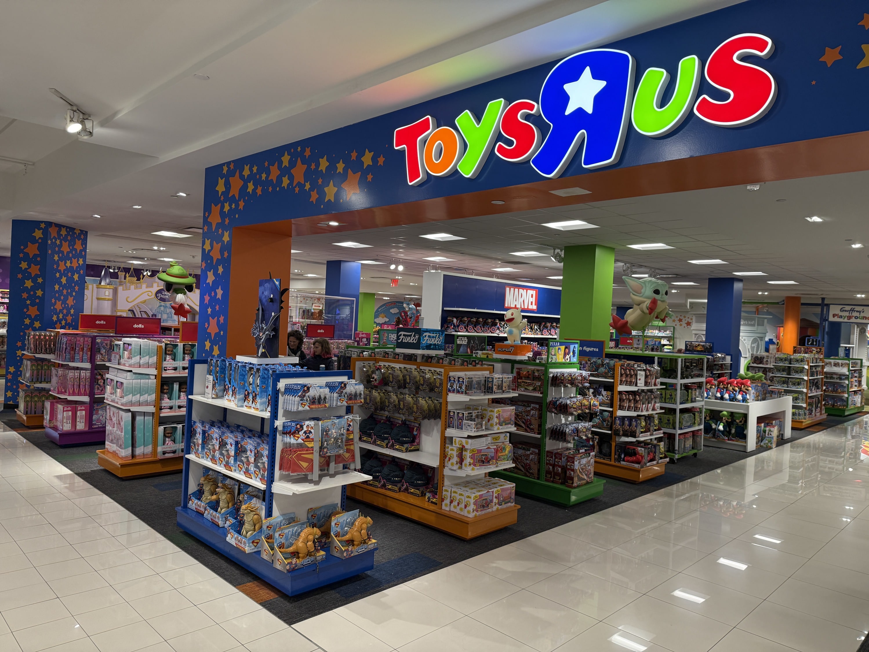 The entrance of Toy R Us inside of a Macy's stores with shelves of toys lining the aisles.