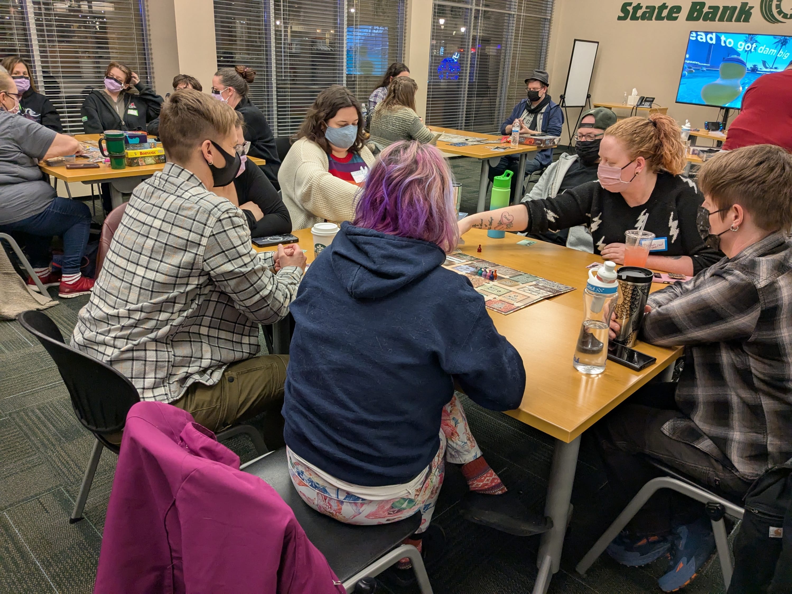 A group of people wearing masks and playing boardgames.