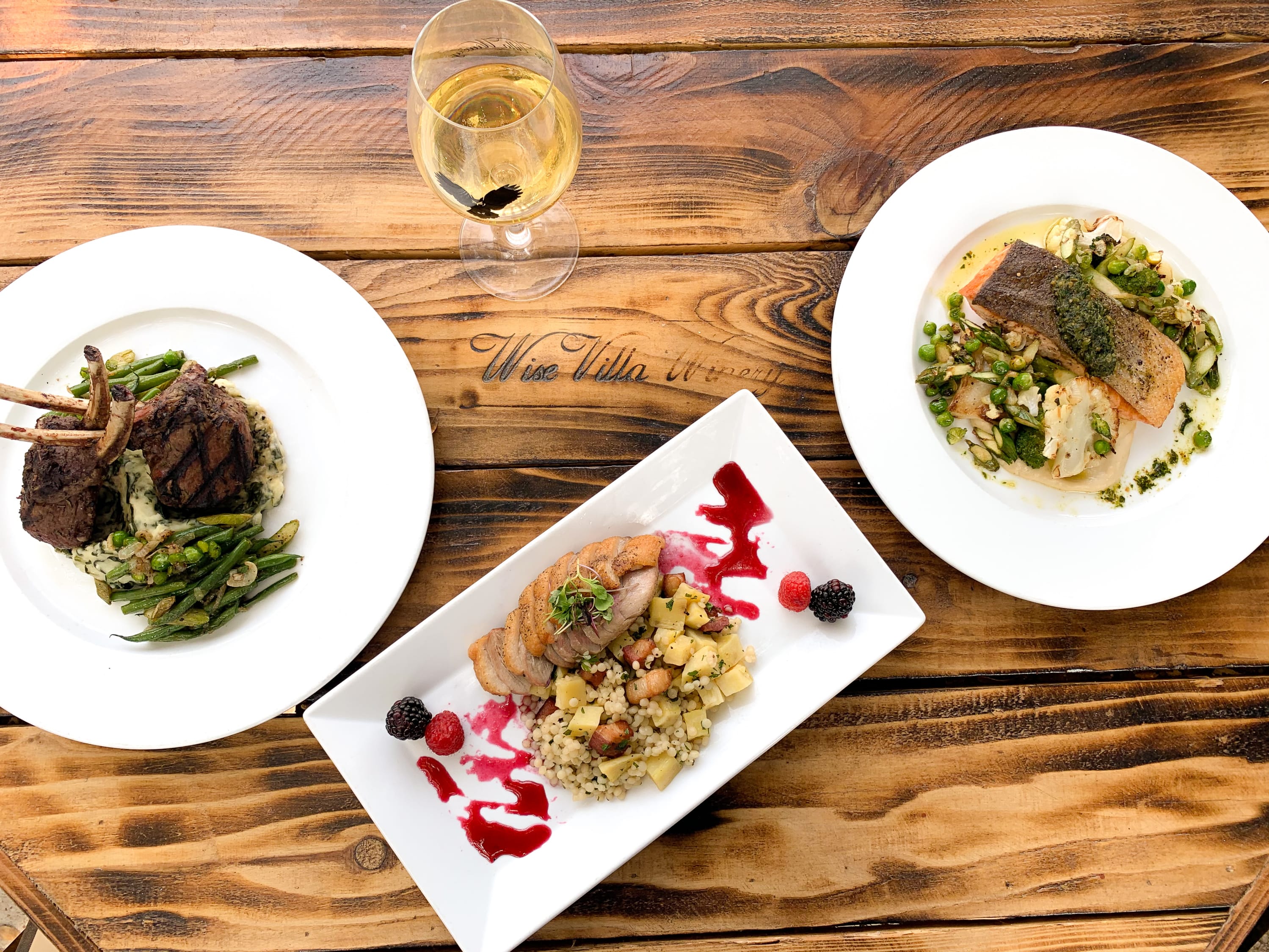 3 plates of food arranged with a glass of white wine